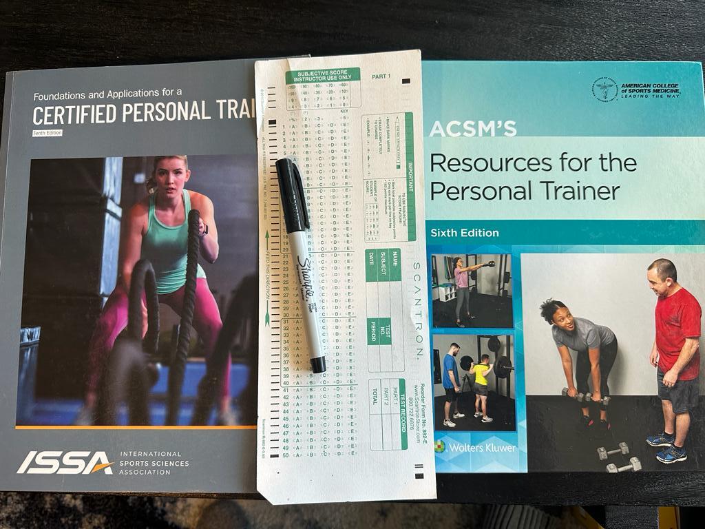 ISSA vs ACSM - Which Fitness Certification is Best? 61 ISSA and ACSM textbooks next to the final exam laid out with a sharpie - which is harder ISSA or ACSM