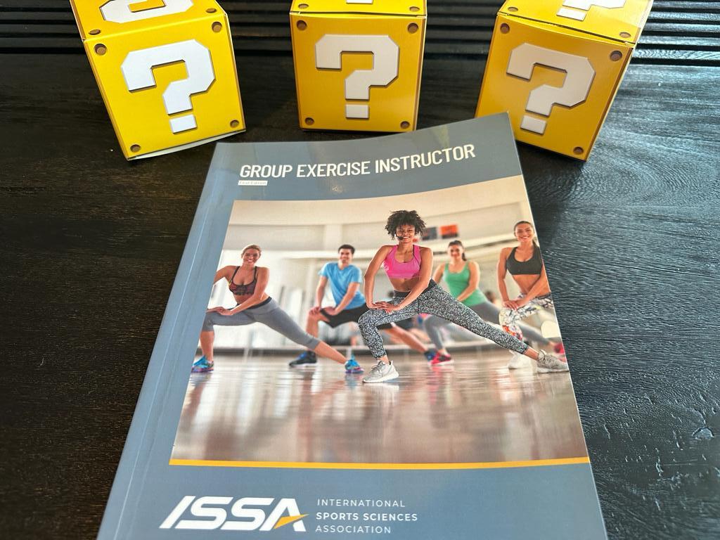 How to pick the best group fitness certification (Updated) 28 best group exercise certifications - ISSA group exercise instructor textbook on table with yellow question mark boxes