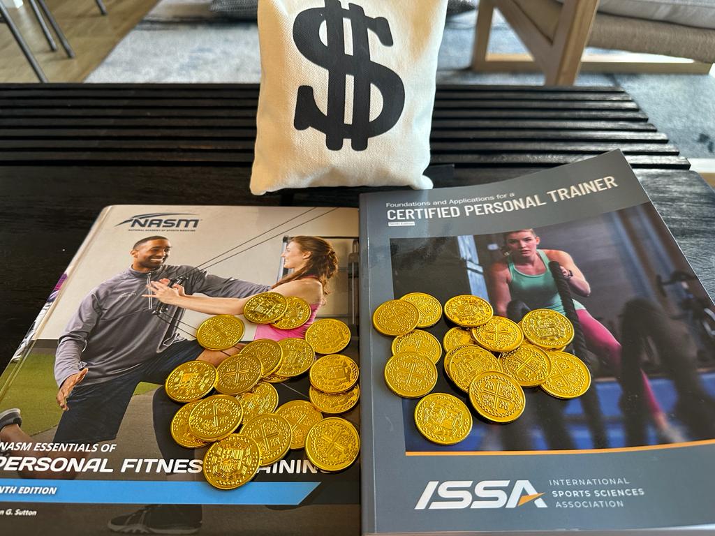 Comparing NASM and ISSA: Which Certification is Right for You? 44 ISSA vs NASM - ISSA and NASM textbooks on desk with gold coins and money bag - which costs more?