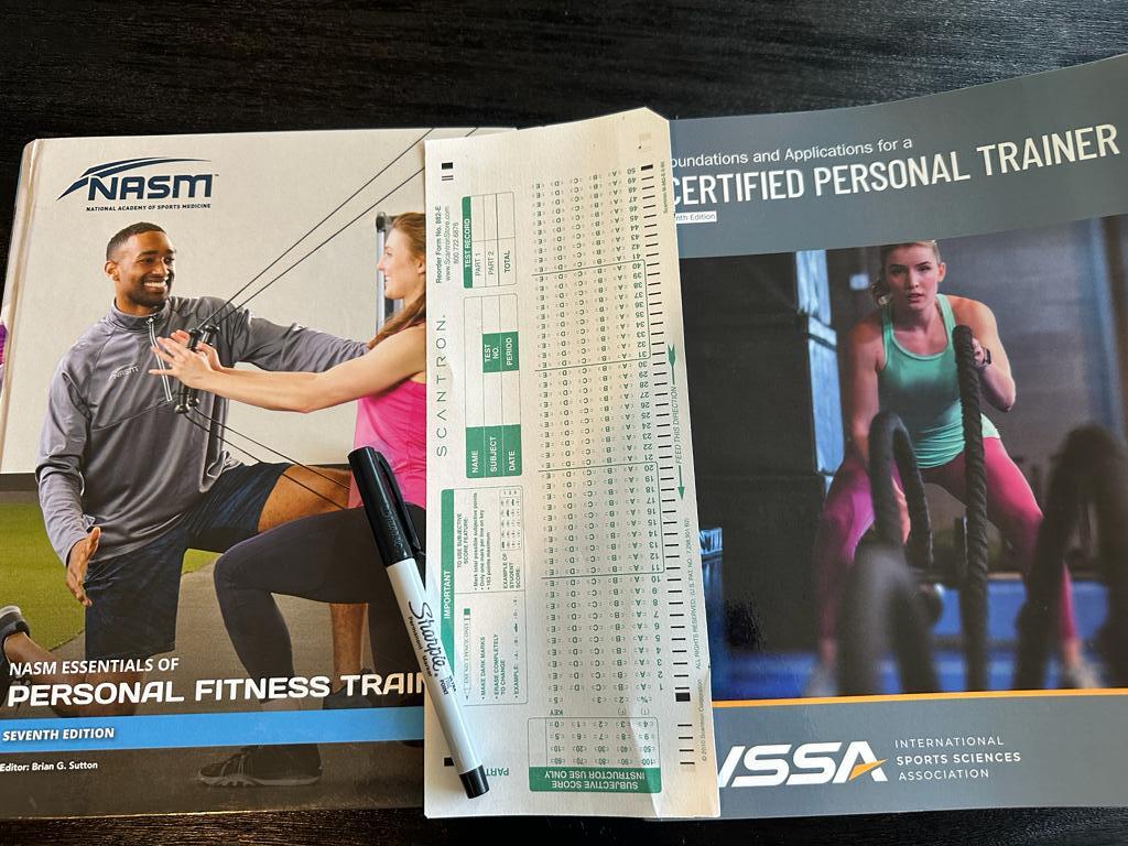 Comparing NASM and ISSA: Which Certification is Right for You? 59 ISSA vs NASM - CPT books next to each other with scantron exam sheet between them and sharpie - which exam is harder