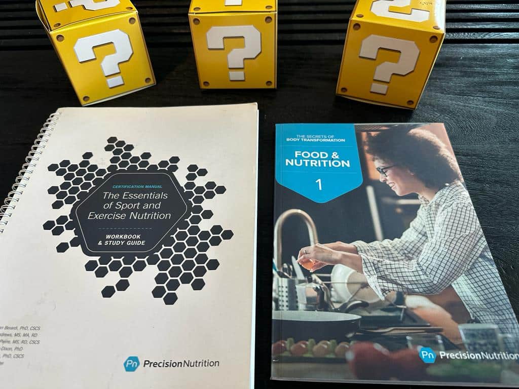 How to pick the best nutrition coach certification (Updated) 49 top nutrition certifications - precision nutrition textbook on table with yellow question mark boxes