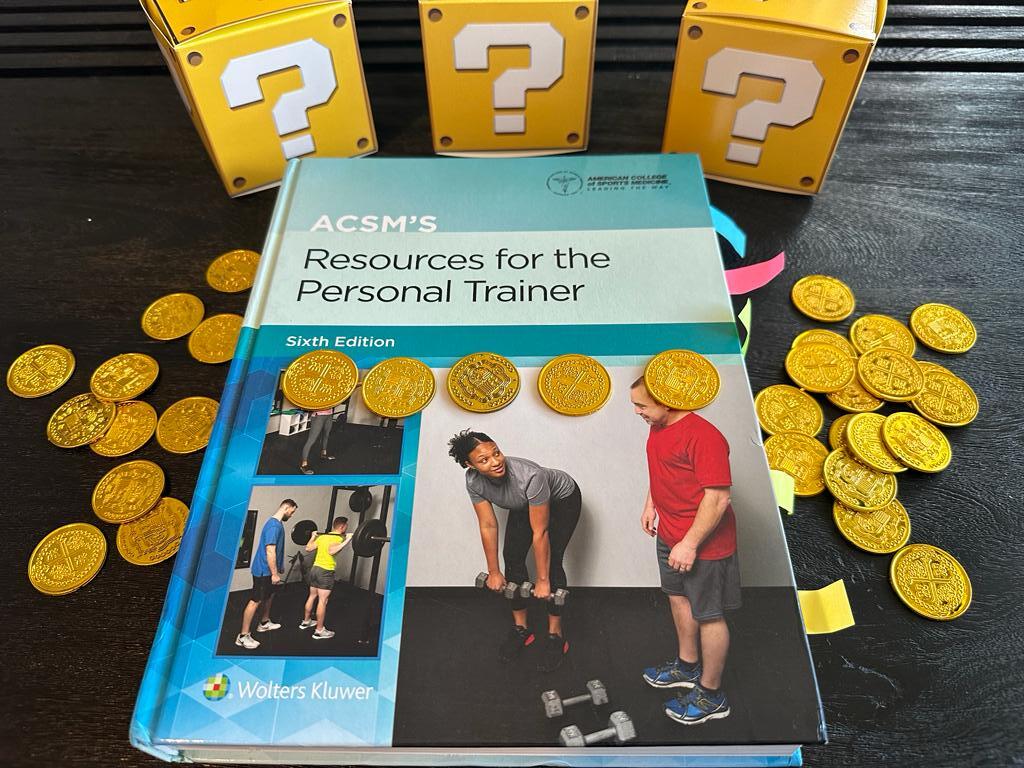 Cheapest personal trainer certification guide (Updated) 37 Cheapest personal training certification - ACSM textbook laid out on table with gold coins and mystery boxes - how much does ACSM CPT cost?