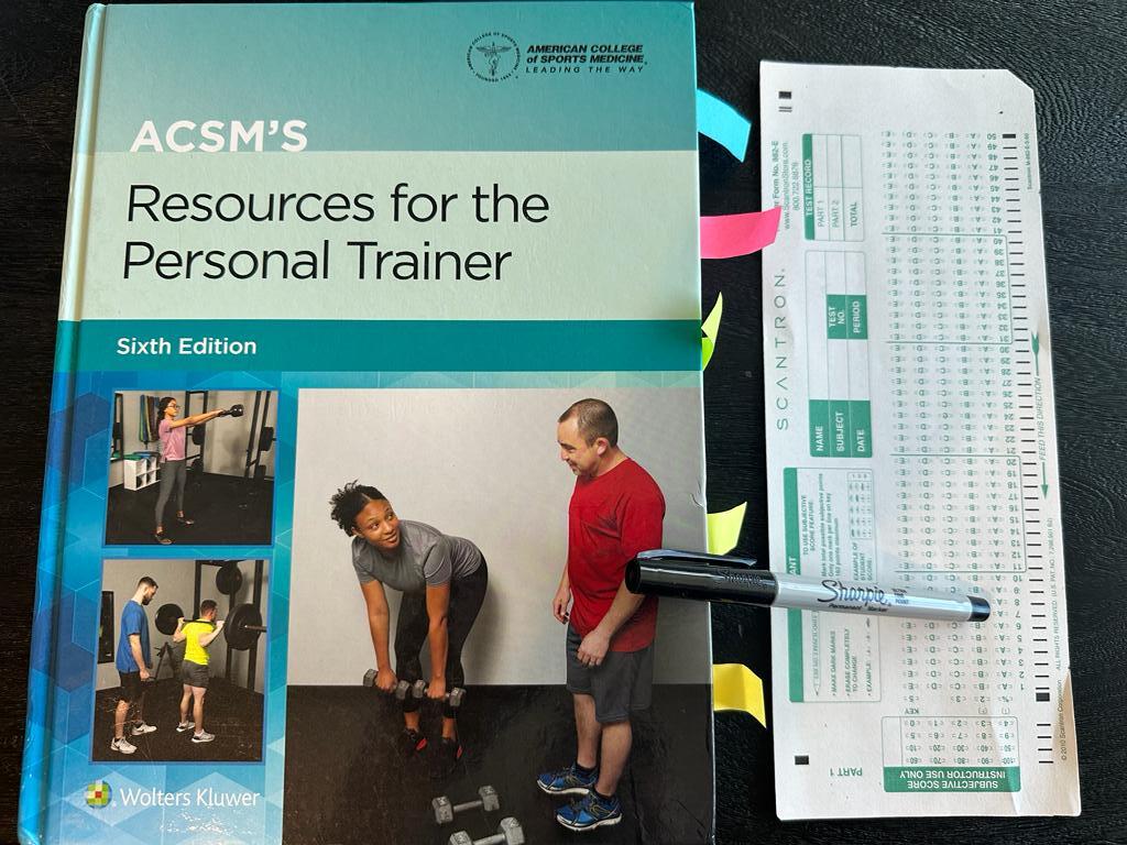 Easiest personal trainer certification guide (Updated) 44 Easiest training certifications - ACSM CPT textbook laid out with a copy of scantron exam next to it and a sharpie