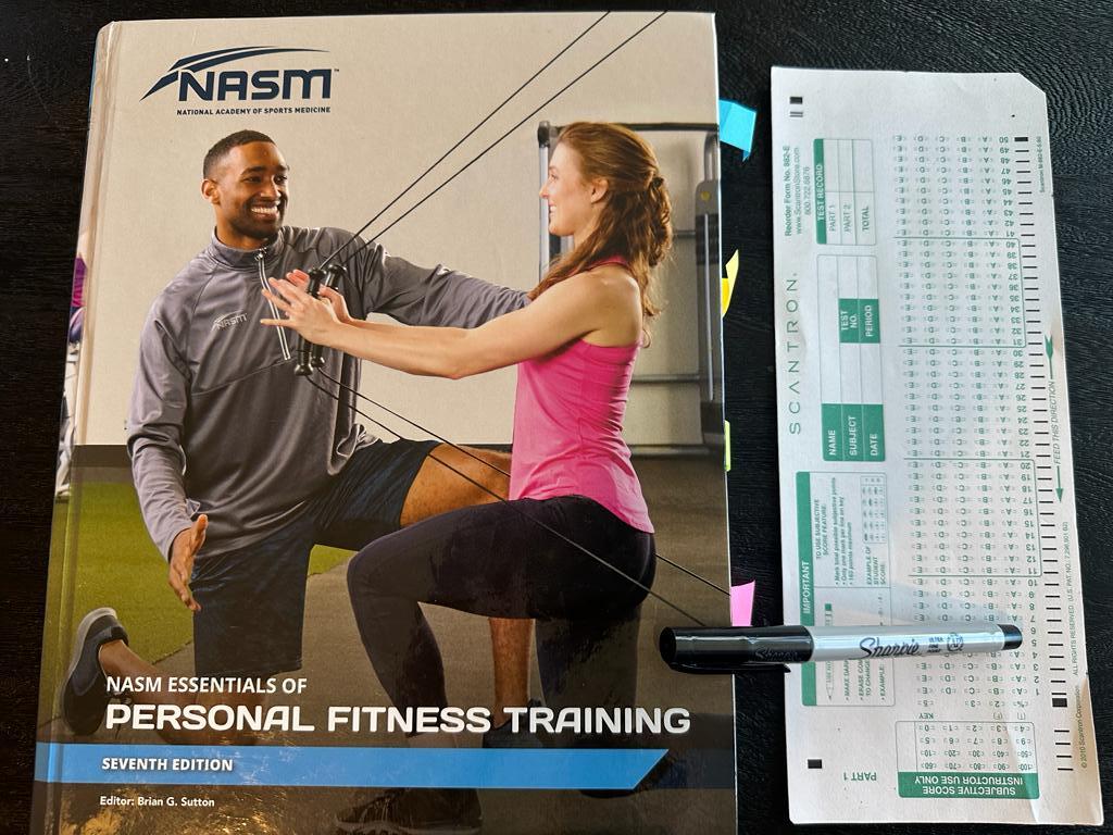 Easiest personal trainer certification guide (Updated) 33 Easy personal trainer certification - NASM CPT textbook laid out with a copy of scantron exam next to it and a sharpie