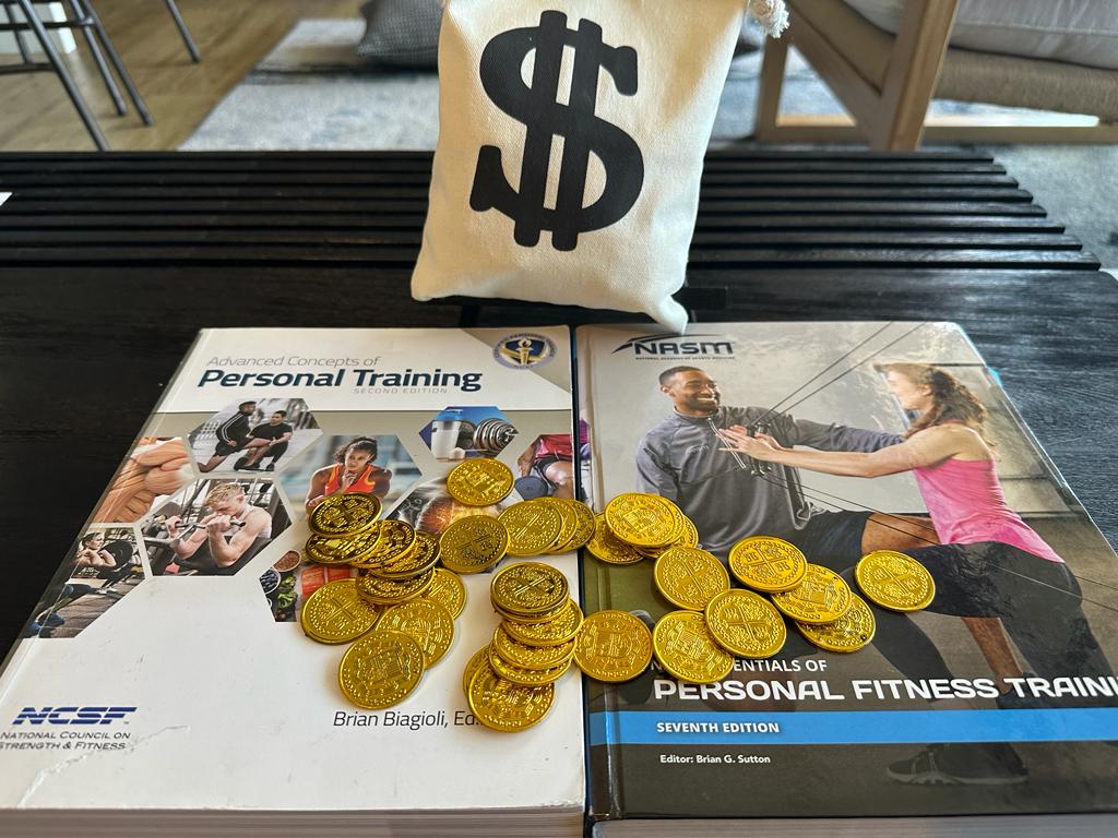 NASM vs NCSF - NCSF and NASM textbooks on table with gold coins and money bag