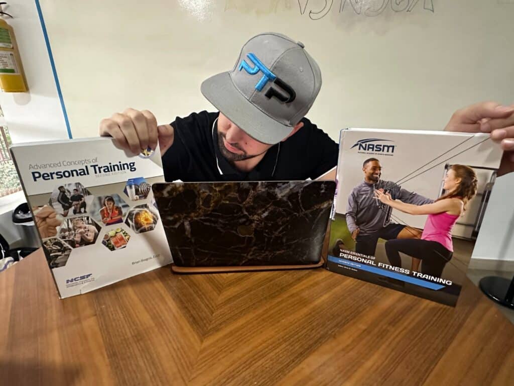 NCSF vs NASM - Tyler Read holds up NCSF and NASM textbooks on table 