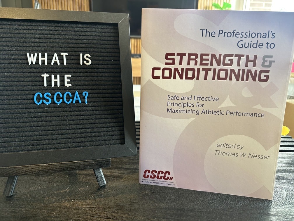 CSCCA Review - Become a Strength & Conditioning Coach 15 CSCCa review - strength and conditioning textbook with sign saying what is the cscca