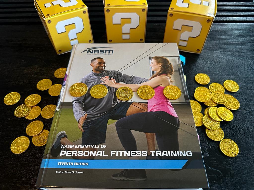Cheapest personal trainer certification guide (Updated) 30 Cheapest personal training certification - NASM CPT. NASM personal trainer textbook displayed on table with gold coins.
