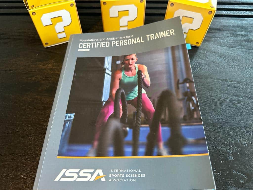 Updated: How to pick the best personal trainer certification 40 ISSA CPT - best personal trainer certification - ISSA CPT textbook laid out with yellow question mark boxes