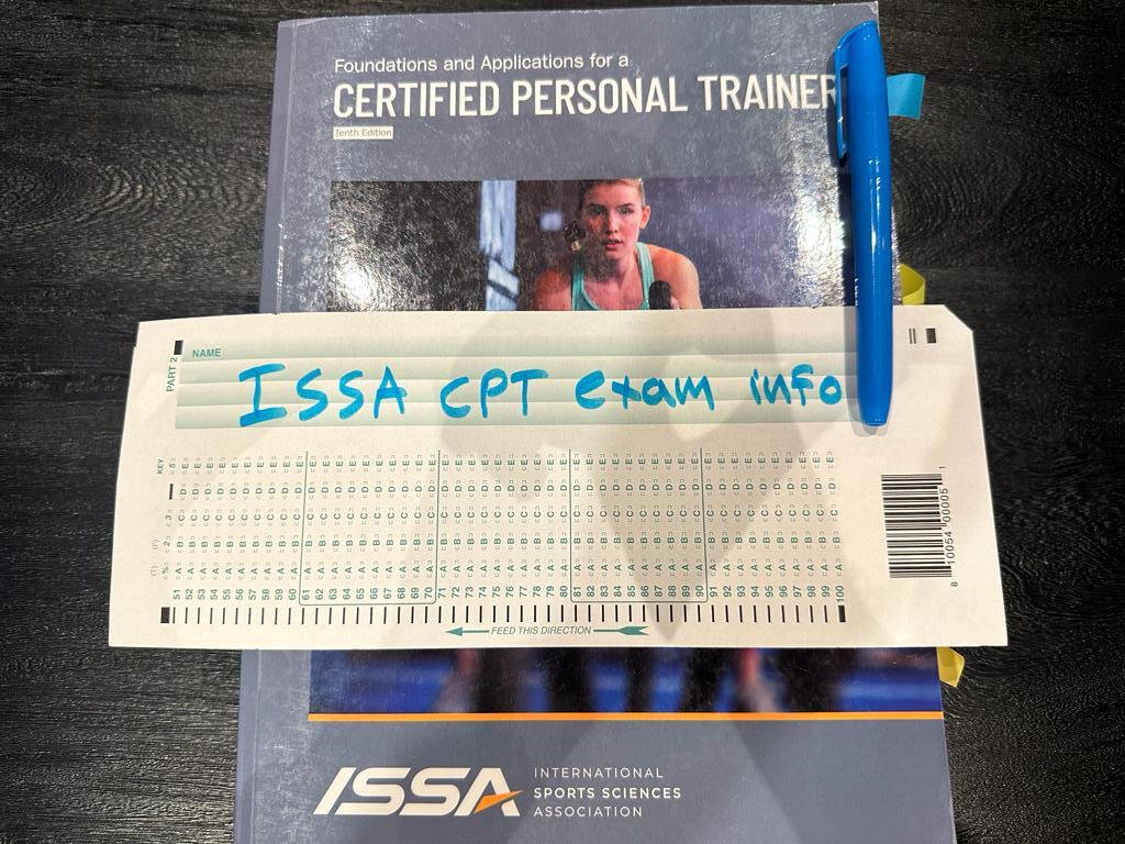 ISSA CPT Exam FAQ - ISSA Pass Rate, Difficulty, Cost 7 ISSA CPT exam info - ISSA personal trainer textbook placed on table with exam information
