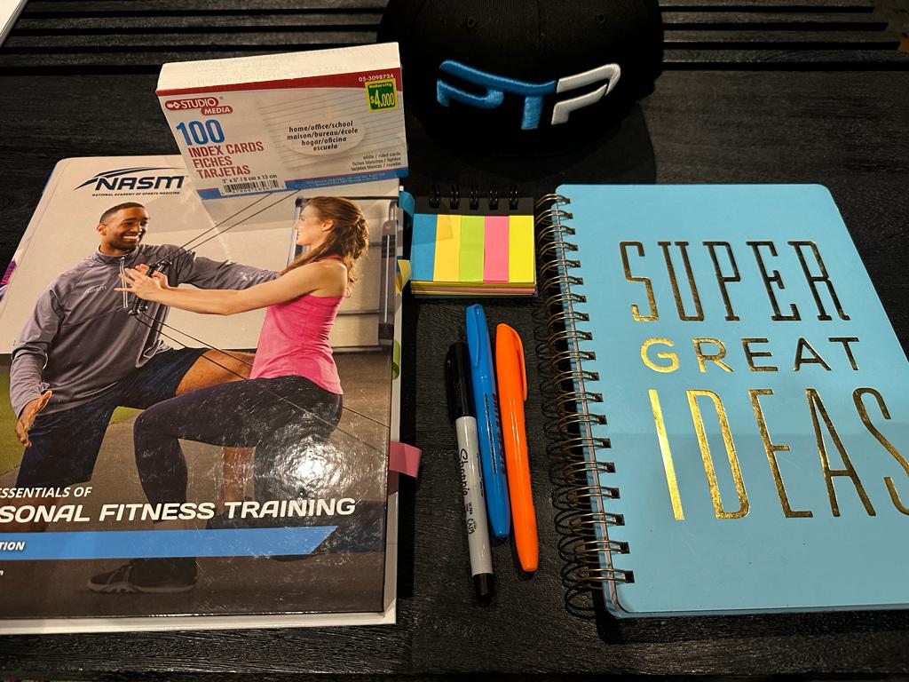 NASM Exam Prep - How to pass the NASM Exam First Try 3 NASM Exam Prep - PT Pioneer - NASM exam prep setup on table with notebook for NASM personal trainer exam preparation