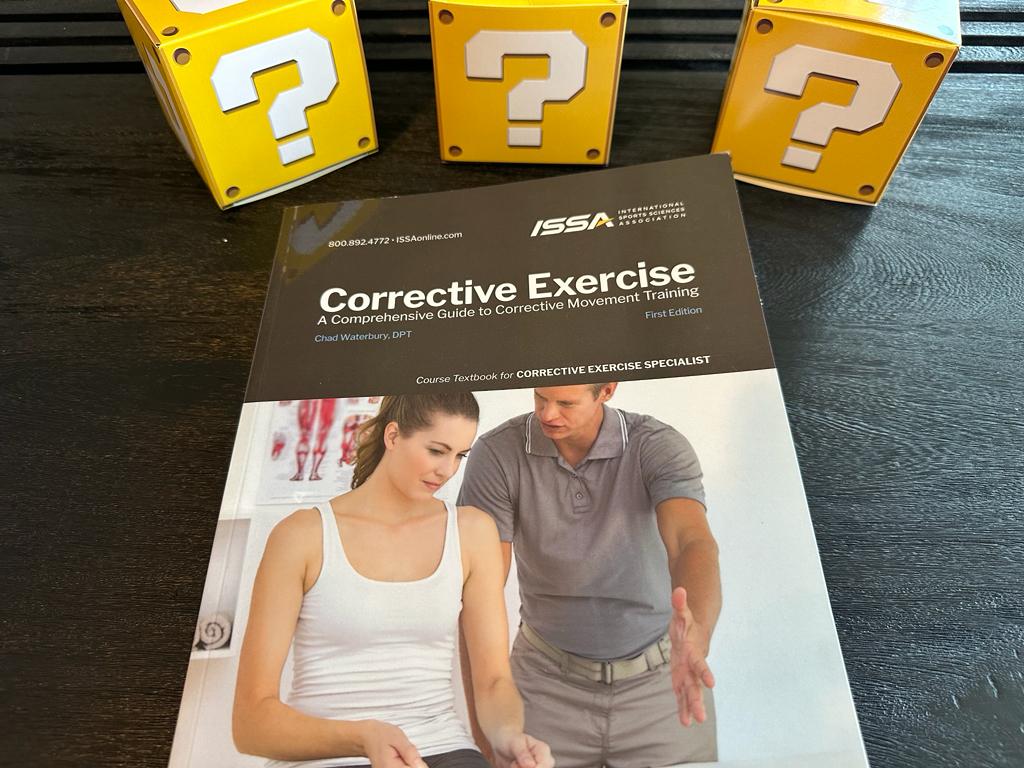 Best corrective exercise certification guide (Updated) 29 best corrective exercise certification - ISSA corrective exercise textbook laid on table with question boxes