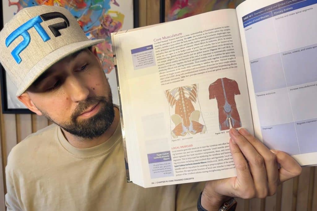 Tyler Read holds up the NASM textbook to a page about the core musculature 