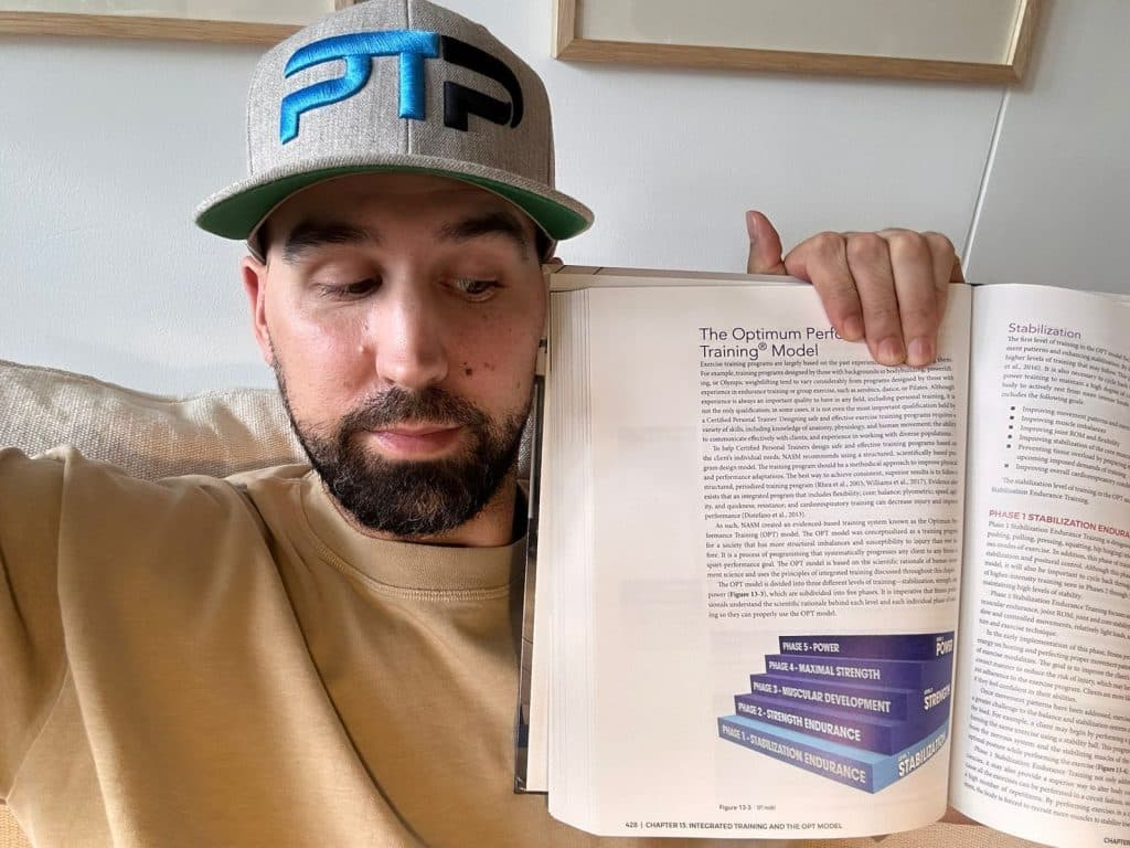 Tyler holding up NASM OPT model textbook 