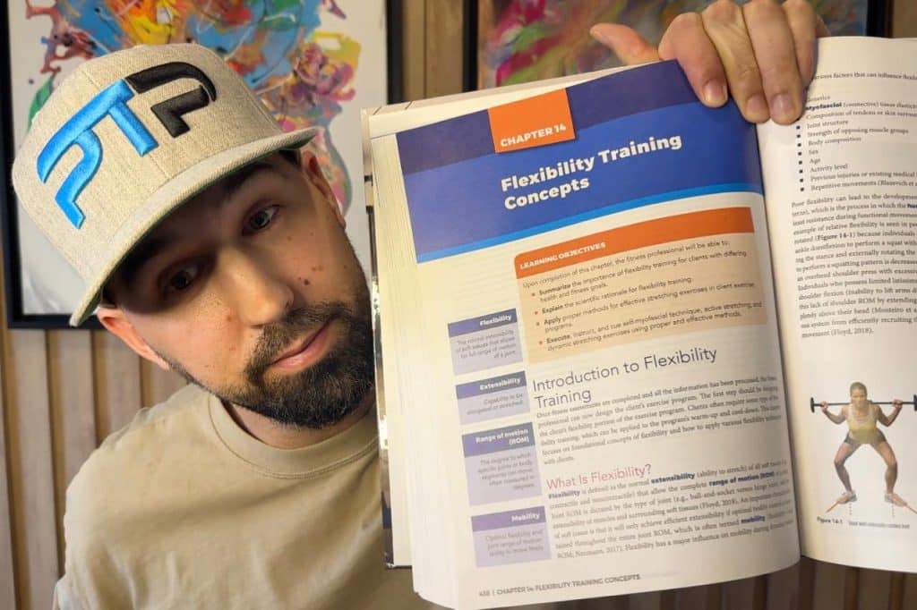 Tyler Read holds up the NASM training textbook showing the chapter on flexibility training concepts 