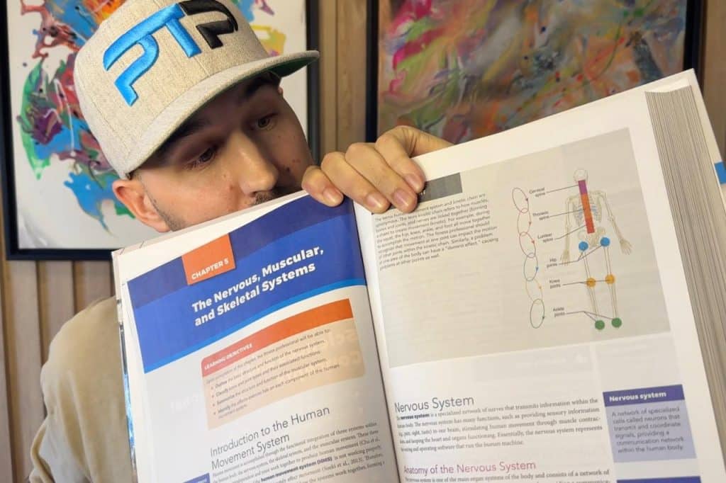 Tyler Read holds up NASM textbook to page describing kinetic chain checkpoints